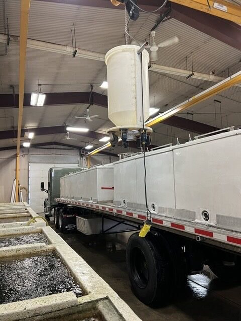 Industrial manufacturing equipment setup with a large white truck and overhead machinery in a factory setting, focusing on industrial processes and equipment for manufacturing.